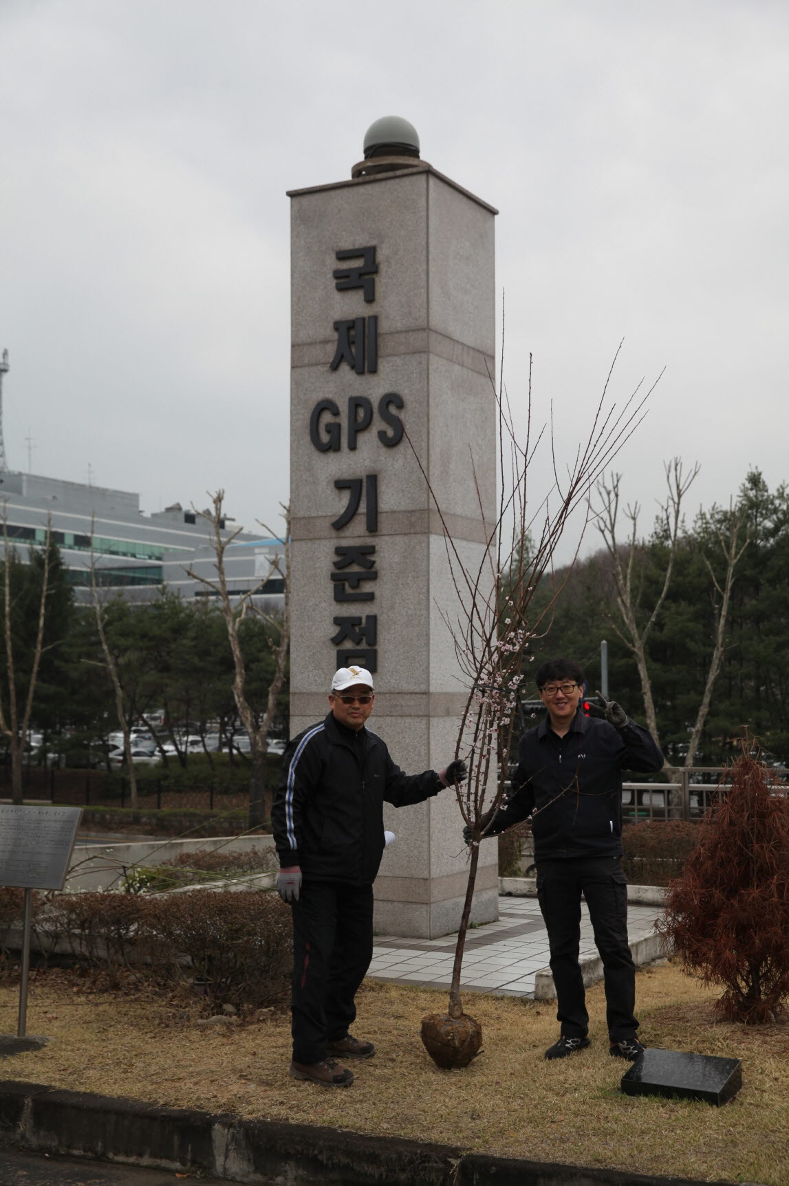 국제 GPS 기준점 앞에서 나무 묘목과 함께 찍은 모습